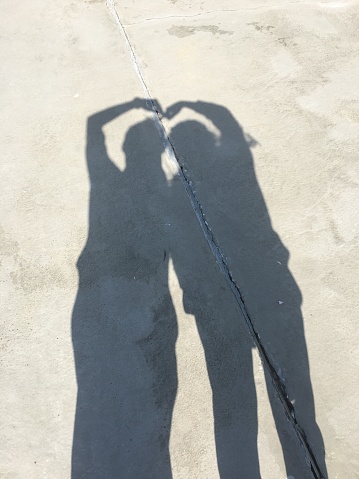 a couple is making heart by shadow