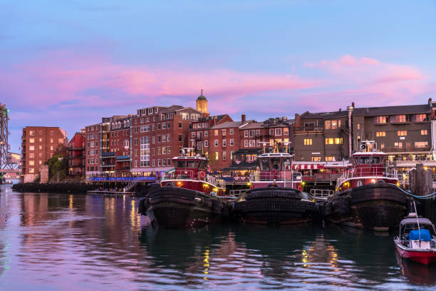 Portsmouth waterfront with moored tug boats at twilight View of Portsmouth waterfront under a majestic colourful sky at dusk. Three moored tug boats are visible in foreground. NH, USA. portsmouth nh stock pictures, royalty-free photos & images