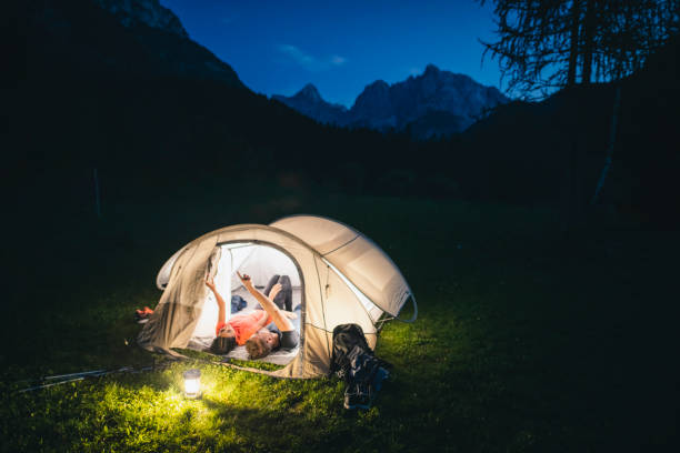 Slovenian couple in 20s and 30s lying on their backs side by side in tent and admiring evening sky.
