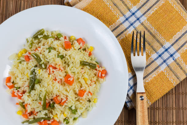 istock Serving of rice with vegetables, fork on napkin, top view 1219875748