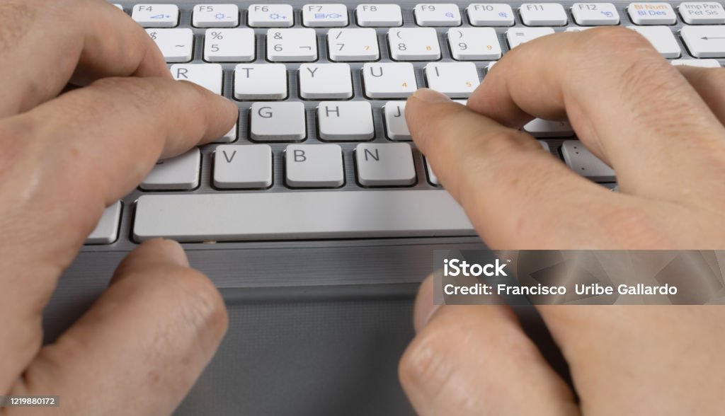 man's hands typing on a gray keyboard with white letters Computer Mouse Stock Photo