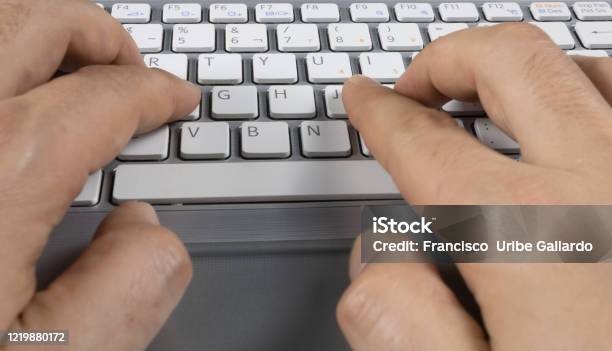 Mans Hands Typing On A Gray Keyboard With White Letters Stock Photo - Download Image Now