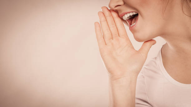 istock Woman talking gossip with hand close to lips 1219881900