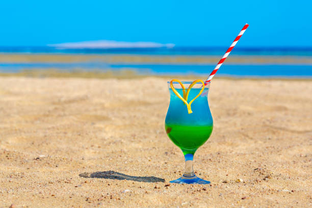 istock Glass with colorful cocktail drink on beach 1219883320