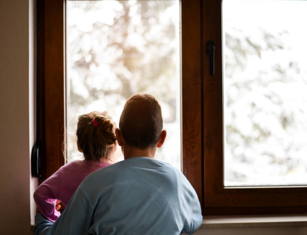 istock Boy and girl from back, looking trough the window. 1219884642