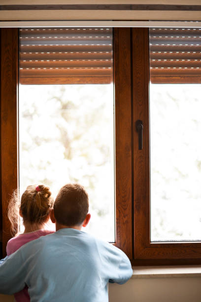 istock Boy and girl from back, looking trough the window. 1219884788