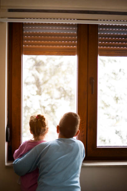 istock Boy and girl from back, looking trough the window. 1219884836