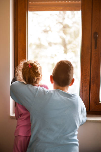 istock Boy and girl from back, looking trough the window. 1219884888