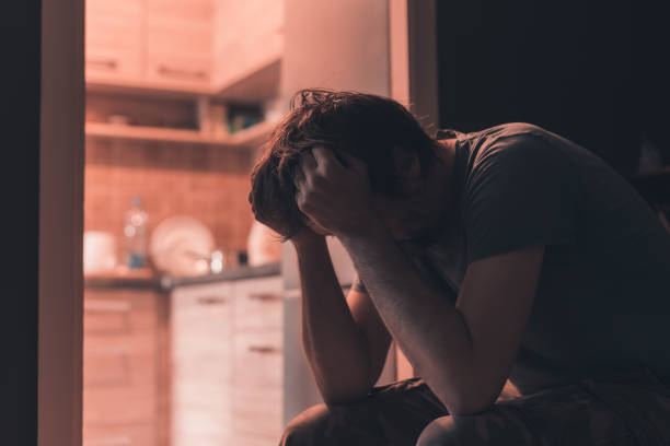 istock Depressed sad man crying in dark room with head in hands 1219885926