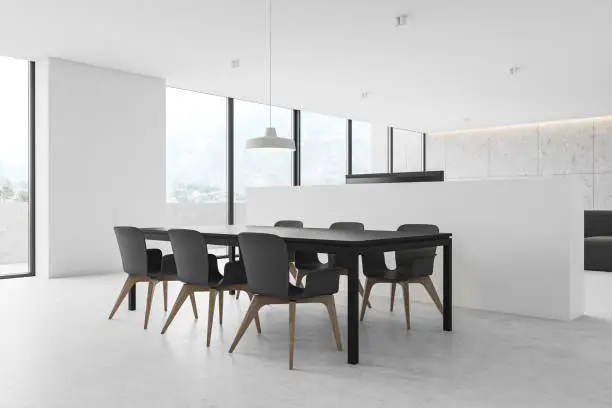 Corner of modern dining room with white walls, concrete floor, grey table with chairs and windows with blurry countryside. 3d rendering