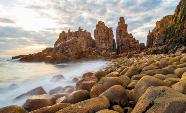 istock Slow moving waves crashing on a beach with mysterious rock formations 1219890410