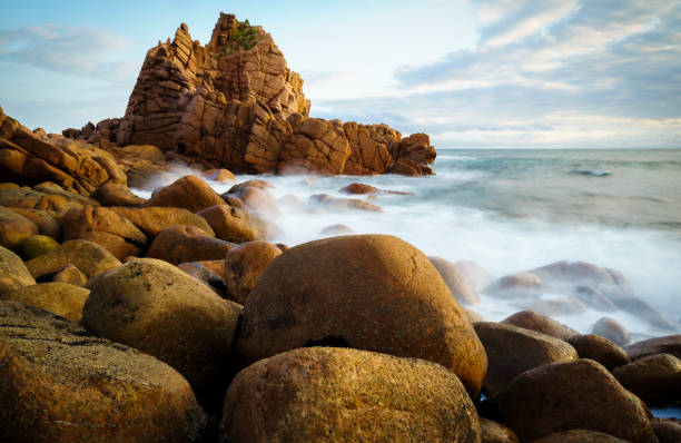 istock Slow moving waves crashing on a beach with mysterious rock formations 1219890490