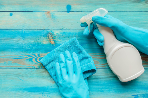 Hands in blue rubber glove holding blue microfiber cleaning cloth and spray bottle with sterilizing liquid make cleaning and disinfection. Cleaning and disinfection. Prevention and control of pandemic