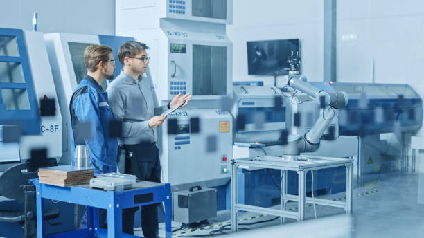 istock In Factory Workshop: Workers Use High-Tech Industrial CNC Machinery, Robot Arm. Inside Office: Digital Engineering Professional Working on Personal Computer, Designing 3D Component in CAD Software 1219894311