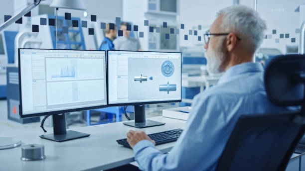 istock In Factory Workshop: Professional Workers Use High-Tech Industrial CNC Machinery, Robot Arm. Inside Office: Digital Engineering Professional Working on PC, Designing 3D Component in CAD Software 1219894336