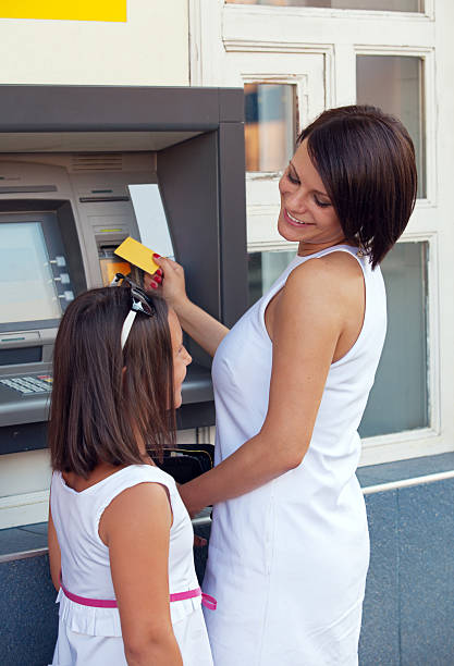 Happy family withdrawing money from credit card at ATM stock photo