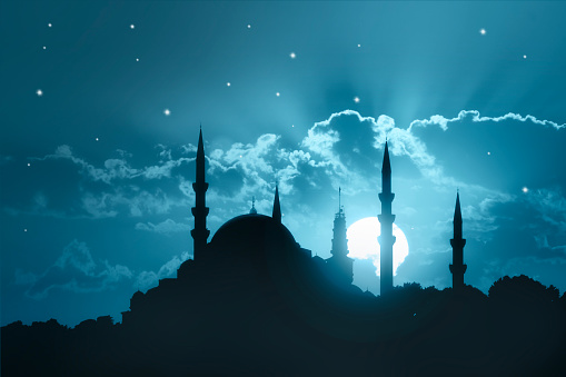 A silhouette of a big mosque on Blue full moon in night background. Ramadan concept