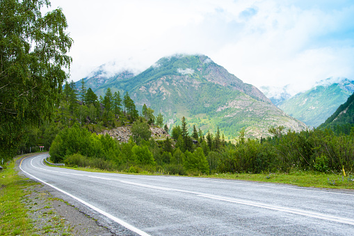 Asphalt road in mountain valley with ridge of rocks on horizon. Comfortable travel by car in wild