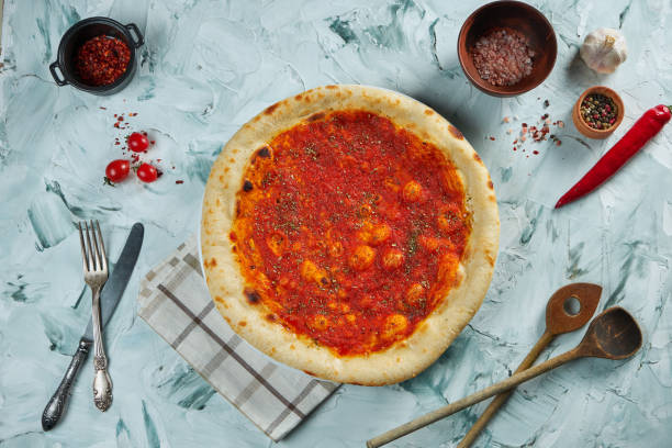 istock Freshly baked crispy pizza with marinara sauce on a gray background in a composition with ingredients and kitchen utensils 1219894989