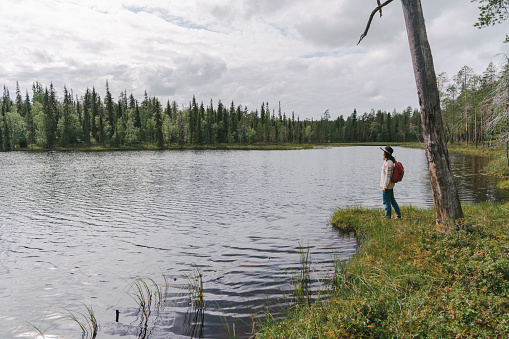 Young Caucasian woman walking in the forest near the river in Finland