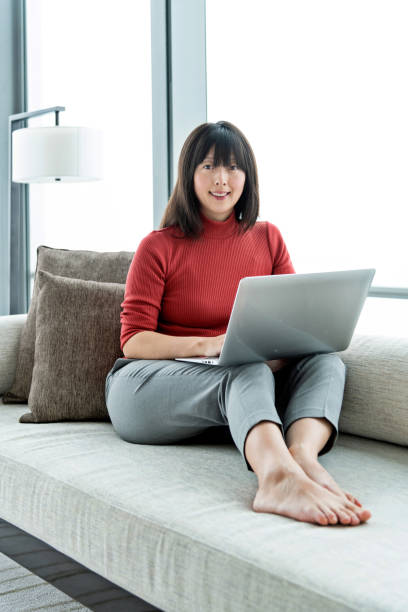 istock Woman sitting on sofa and using laptop 1219900224