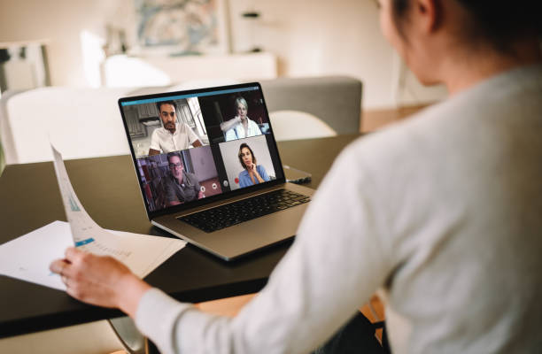 Businesswoman at home having a video conference with her team Group of business people working from home, having video conference. Businesswoman having a video call with her team over a laptop at home. lockdown business stock pictures, royalty-free photos & images