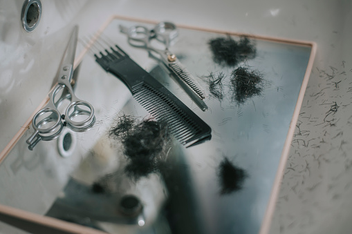 scissors , comb and mirror with hairs after the haircut at sink in bathroom