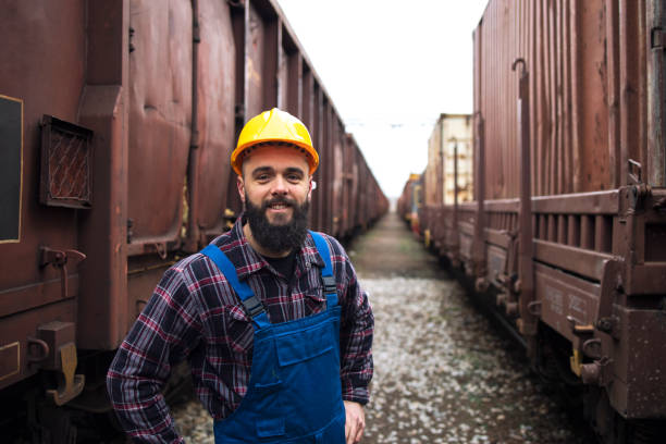 istock Portrait of smiling railroad worker standing between freight trains. 1219904143