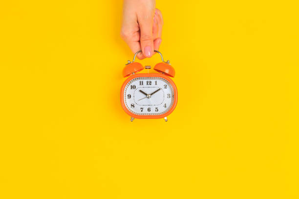 istock Beautiful young woman's hands with alarm clock  on pastel  background - Image 1219904213