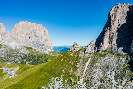 Aerial view of Italian alps - Langkofel (The Saslonch, Sassolungo) mountains, surrounded by green meadows and alpine road.