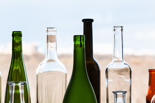 various empty bottles and view of city park through home window on sunny spring day on background