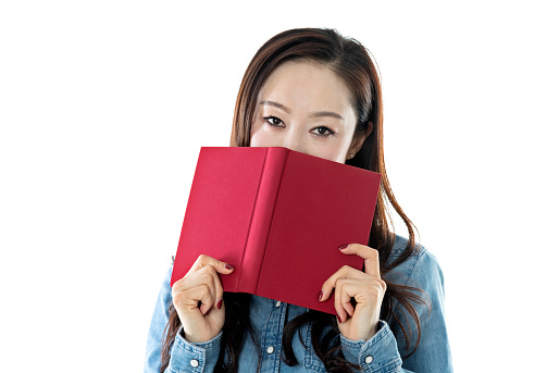 Woman hiding behind a book on white background.