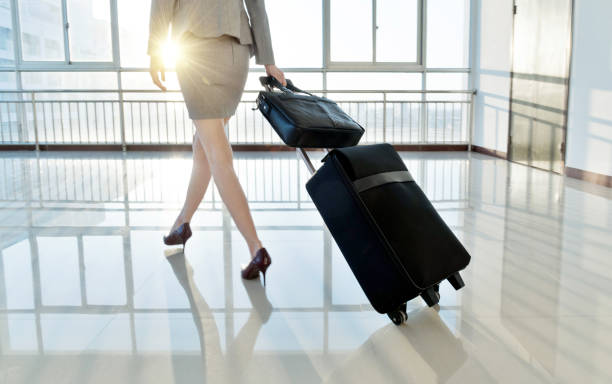 istock Businesswoman pulling a suitcase walking on entrance hall 1219918089