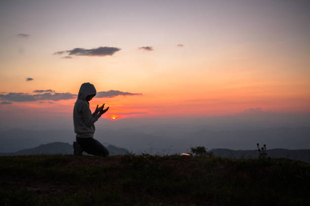 una niña cristiana reza a dios en la cima de la montaña y la puesta del sol. creencias religiosas, copiar espacio. - god freedom arms raised high angle view fotografías e imágenes de stock