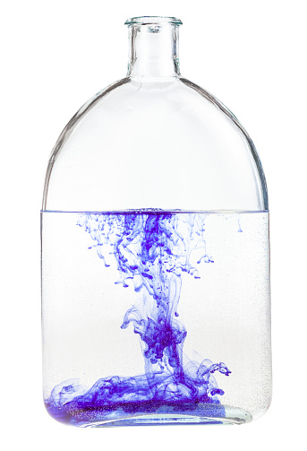 violet watercolour dissolves in water in glass flask isolated on white background