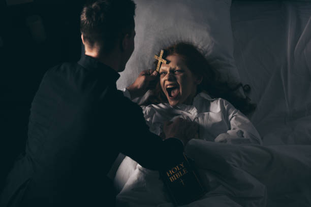 male exorcist with bible and cross standing over demoniacal screaming girl in bed male exorcist with bible and cross standing over demoniacal screaming girl in bed exorcism stock pictures, royalty-free photos & images