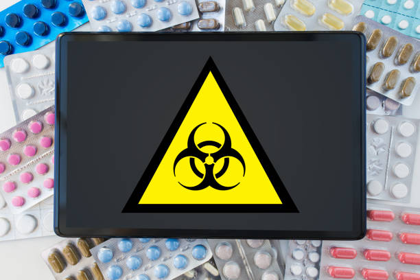 istock boihazard caution sign, tablet pc and drugs 1219922280