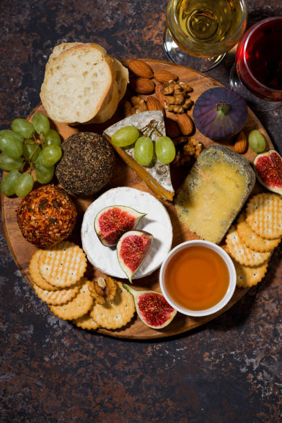 istock cheese, crackers and fruits, delicious wine snacks on dark background, vertical top iew 1219923741