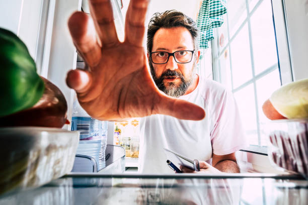 homem caucasiano adulto levar comida saudável de uma geladeira aberta - close-up dentro da vista - conceito de perda de peso - atividade doméstica na cozinha - quarentena coronavirus pessoas conceito ficar em casa - come in were open - fotografias e filmes do acervo