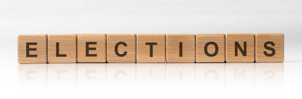 istock Elections Word Written In Wooden Cubes on white glossy background with reflection 1219924803
