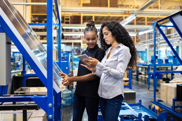 Supervisor and worker discussing work on digital tablet Female engineer showing the production plan to a worker on her digital tablet. Supervisor and female worker looking at digital tablet and discussing work in factory shop floor. solar panel manufacturing stock pictures, royalty-free photos & images