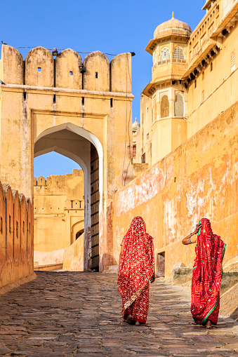 Two Indian women, wearing saris, are going up the way to Amber Fort near Jaipur, Rajasthan.  Amber Fort is located 13km from Jaipur, Rajasthan state, India. It was the ancient citadel of the ruling Kachhawa clan of Amber, before the capital was shifted to present day Jaipur.