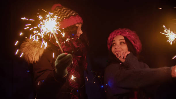 istock Two young women friends walking outdoors holding bright sparklers 1219929051