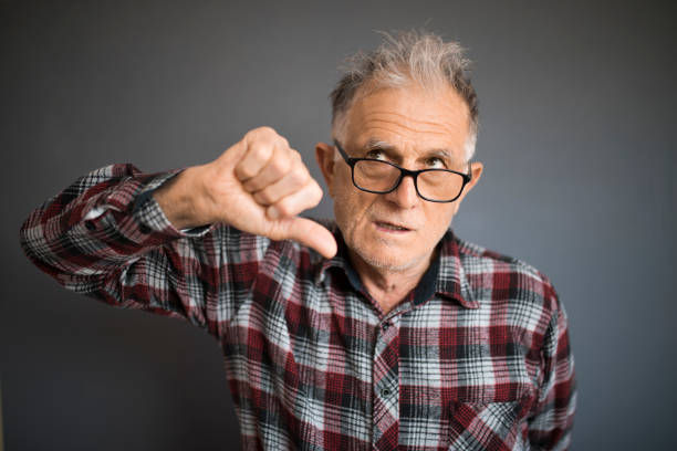 istock Senior man with funny messy hair points his thumb down 1219929467