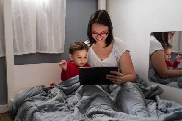 Mother and son with tablet in bed