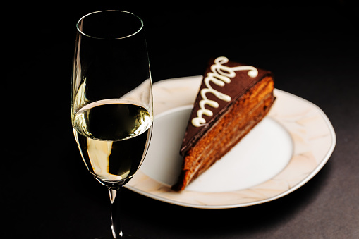 Close-up view of a sparkling wine glass with a slice of cake.