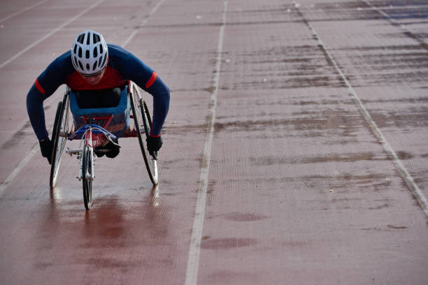 Paraplegic male athlete in racing wheelchair warming up alone outdoors Preparing for wheelchair marathon. Paraplegic male athlete in racing wheelchair warming up alone at outdoor track and field stadium athlete with disabilities photos stock pictures, royalty-free photos & images