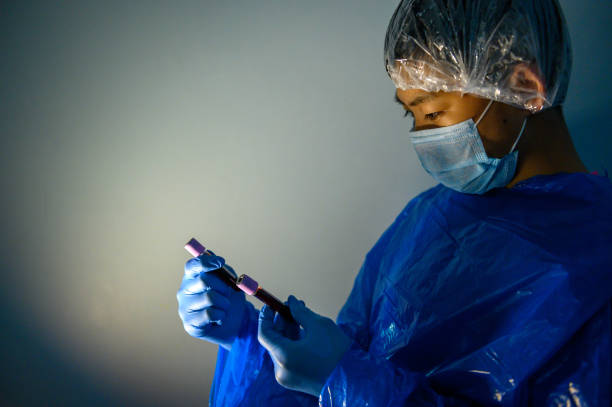 istock Young laborant in hazmat protective suit holding Coronavirus blood sample for Covid-19 test 1219933747