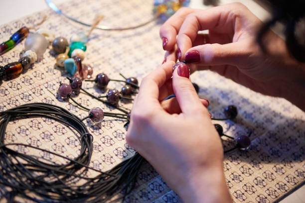 istock Hands of young craftswoman holding black plastic thread and glass bead 1219934642