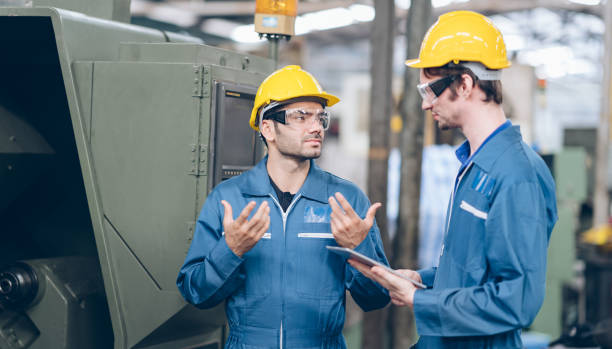 istock technician engineer and Apprentice operate heavy machine to automated CNC in factory 1219935696